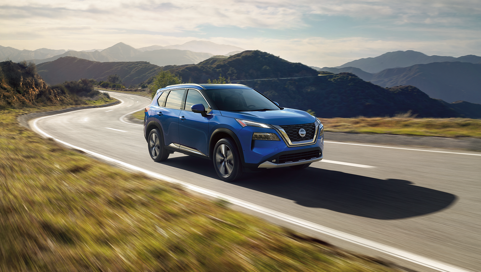 Blue Nissan Rouge running on road